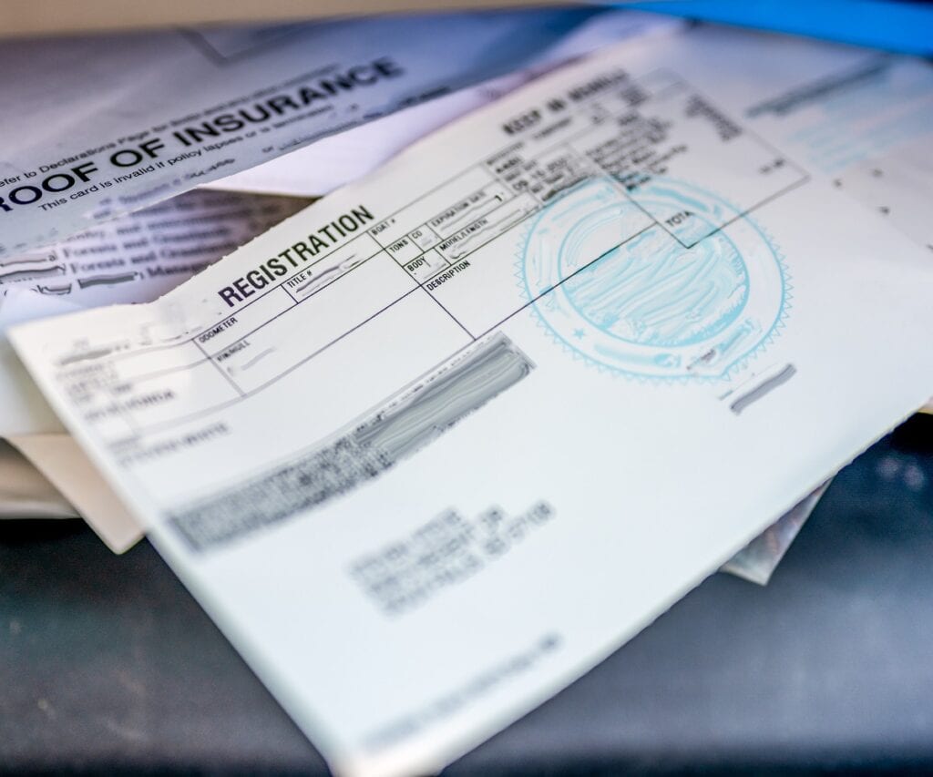 Versicherungsnachweis und Fahrzeugschein im Handschuhfach eines Autos.