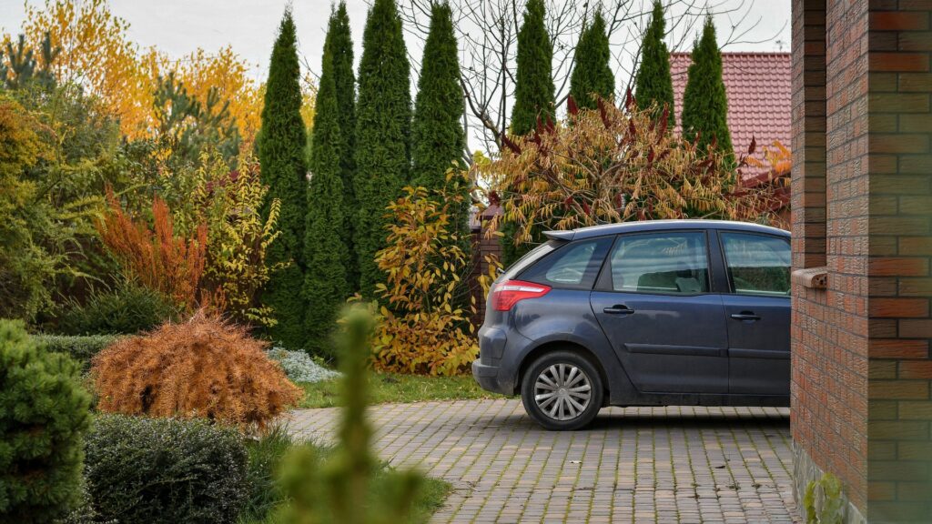 Der hintere Teil des Autos parkt in der Nähe der Garage im Hintergrund des Gartens.
