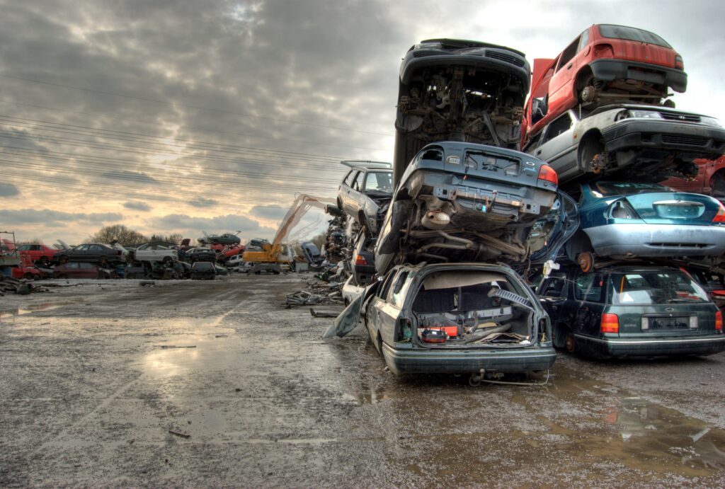 Bagger auf einem Schrottplatz, der beschädigte Autos recycelt
